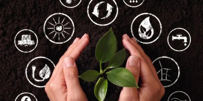 Top-down view of hands cupping a small green plant in dark soil, surrounded by a circle of sustainability and environmental icons.