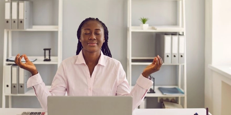 A business owner meditating at her desk to find clarity while researching eco-friendly pest control and avoiding greenwashed products.